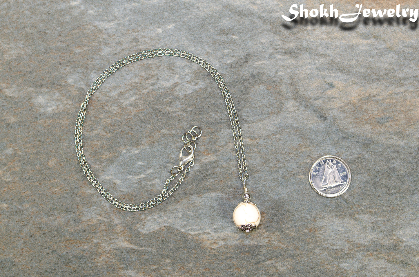 12mm White Howlite Pendant Necklace beside a dime.