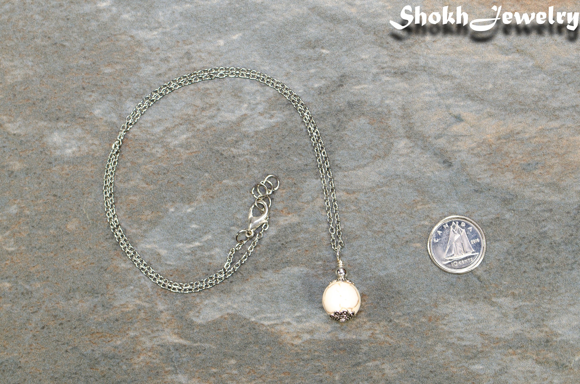 12mm White Howlite Pendant Necklace beside a dime.