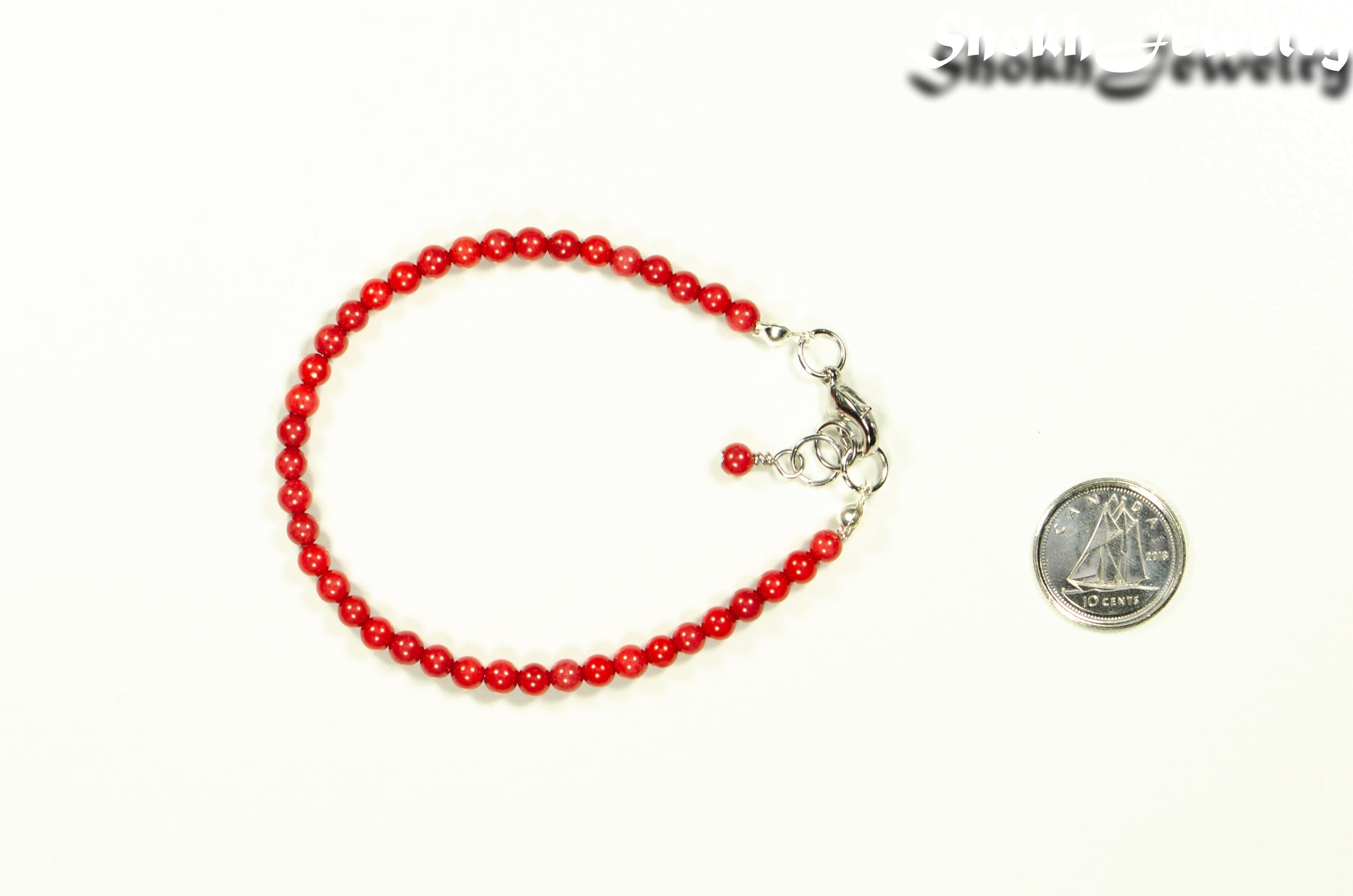 4mm Natural Red Coral Bracelet with Clasp beside a dime.