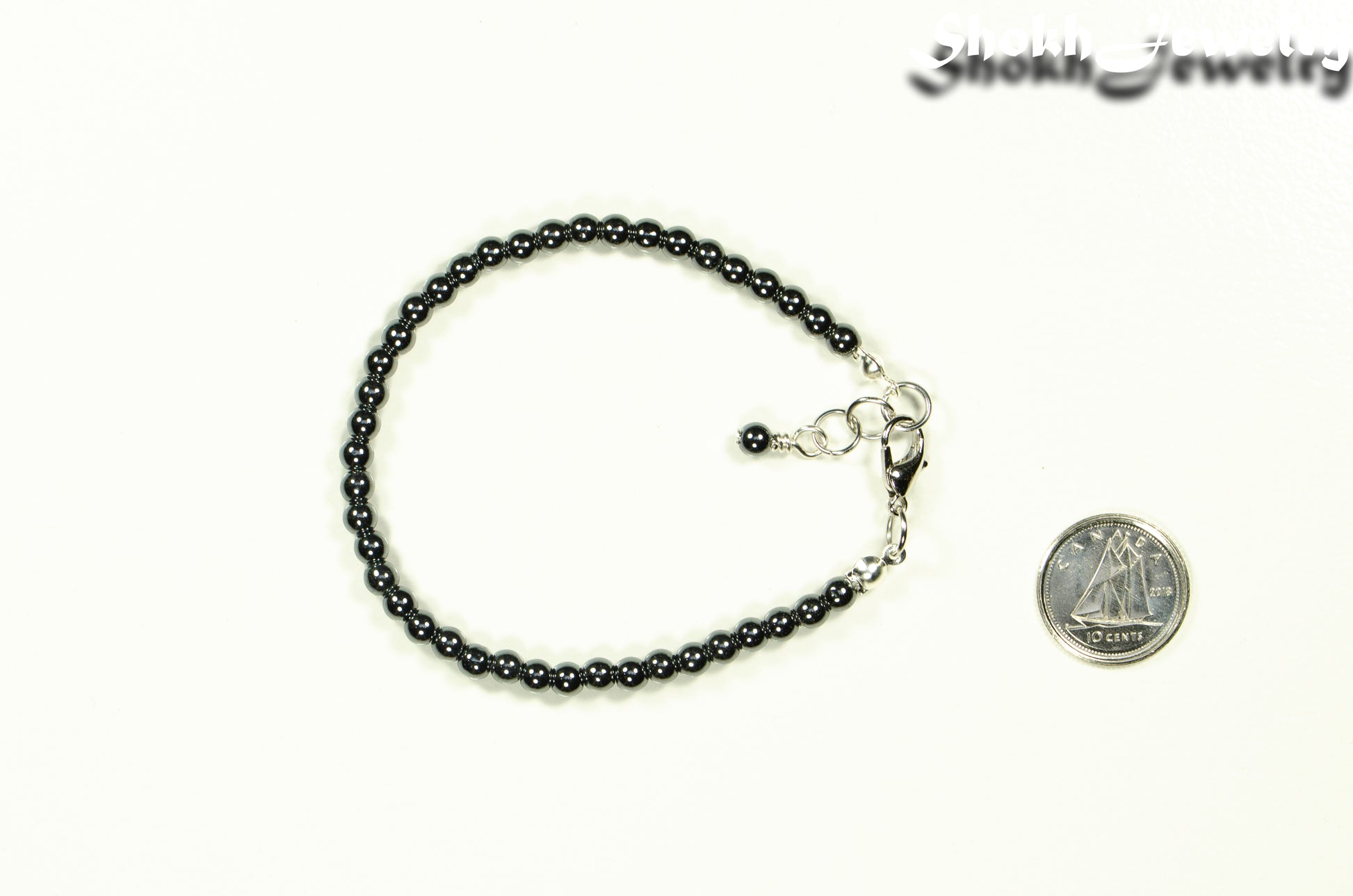 4mm Hematite Stone Bracelet with Clasp beside a dime.